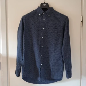 Uniqlo skjorta mörkblå prickig - Oanvänd mörkblå skjorta med vita prickar i storlek M från Uniqlo.   Längd 77cm Underarm 43cm Axelbredd 45cm
