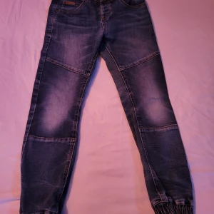 Jeans Strl 128 - Jeans från Kappahl i strl 128. Kommer från djur och rökfritt hem. Resår nere vid fötterna. Fint skick.