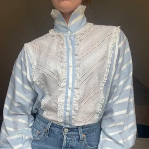 Blus / skorta med spetsdetaljer - Fin blus med spetsdetaljer. Blusen är vintage från 70-talet, och är gjort utav 100% bomull. Blusen har en liten fläck som går att se på bild 3. Blusen är storlek 38, Modellen är 166 cm lång och storlek s