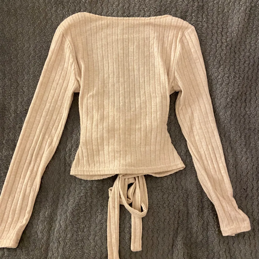 Långärmad beige tröja med öppen rygg och rosett. Materialet är tunt men mjukt och den är i storlek XS men passar mig som har S, bara använd en gång❣️. Tröjor & Koftor.