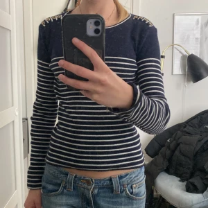 En långärmad tröja med mönster  - Långärmad tröja med mönster med gulddetaljer vid axlarna.