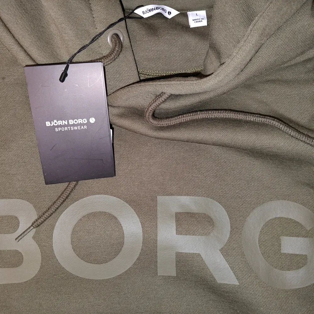 Mörkgrön/olivgrön Björn Borg hoodie i storlek large. Skönt material och varm med bra passform. Säljer då den inte är min stil längre. Helt oanvänd. Skriv vid minsta fundering eller för fler bilder!. Hoodies.