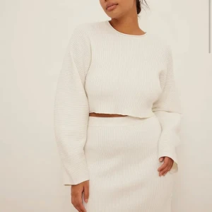 Cropped Knitted Wide Sleeve Sweater - Den här tröjan är croppad och har breda långa ärmar och en ribbstickning. Vit. Storlek S/M. Aldrig använd.  Originalpris: 549kr