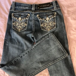 L.A. Idol jeans - Lågmidjade bootcut jeans.  Massa bling både fram och bak✨  Inget slitage. Lite stretch i sig  Midja rakt över: 33,5 cm  Innebenslängd: 77