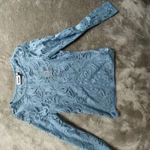 En ljusblå genomskinlig, långärmad tröja i ett fint mönster