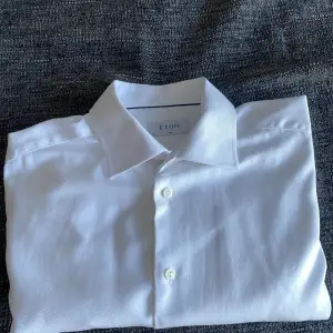 En jättefin vit skjorta från Eton i mycket bra skick. Det är en liten vit fläck på ryggen som syns på bilderna. Den syns dock inte när man har på sig den. Skriv för fler bilder. 
