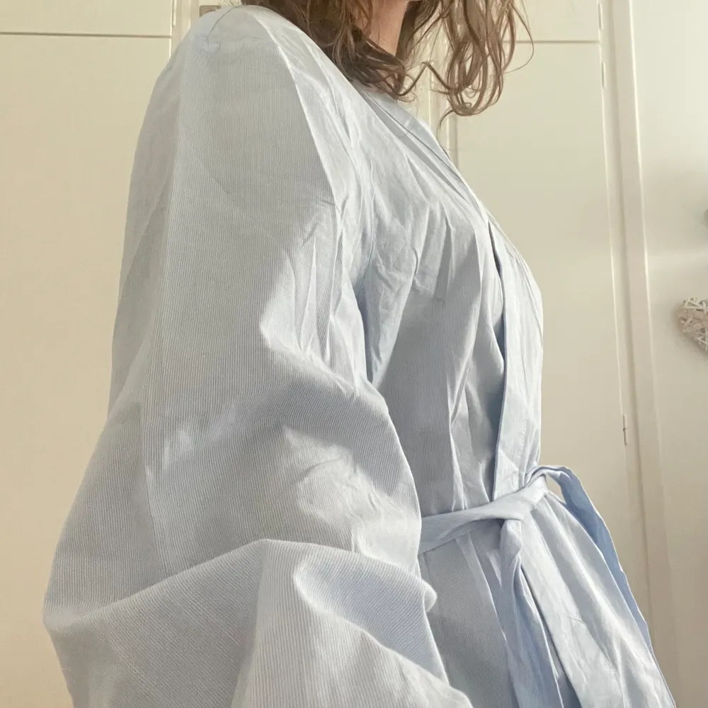 En superluftig och skön morgonrock i ett ”skjort-aktigt” material, perfekt till sommaren!💕 Kollar man närmre så är den lite vit- och blårandig. Den är i storlek S och man kan spänna in och ut midjesnöret!🫶🏼. Muu.