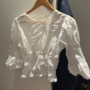 Vit blus - Använda några gånger, tvättad därav skrynklig (kan strykas om önskas), säljs eftersom jag ej använder längre Inga defekter utom att lappen med butiksnamn är avklippt 