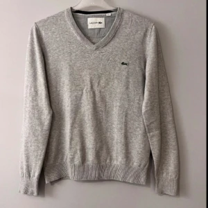 Grå Lacoste Tröja - V-neck tröja från Lacoste . Inte sönder men har lite ljusare märken bland det gråa(inte mer än vad som syns på bilderna). Skick: 7/10. Storlek: S eller XS. Funderingar samt prisförslag välkomnas! LIKNANDE PLAGG PÅ PROFILEN  17 