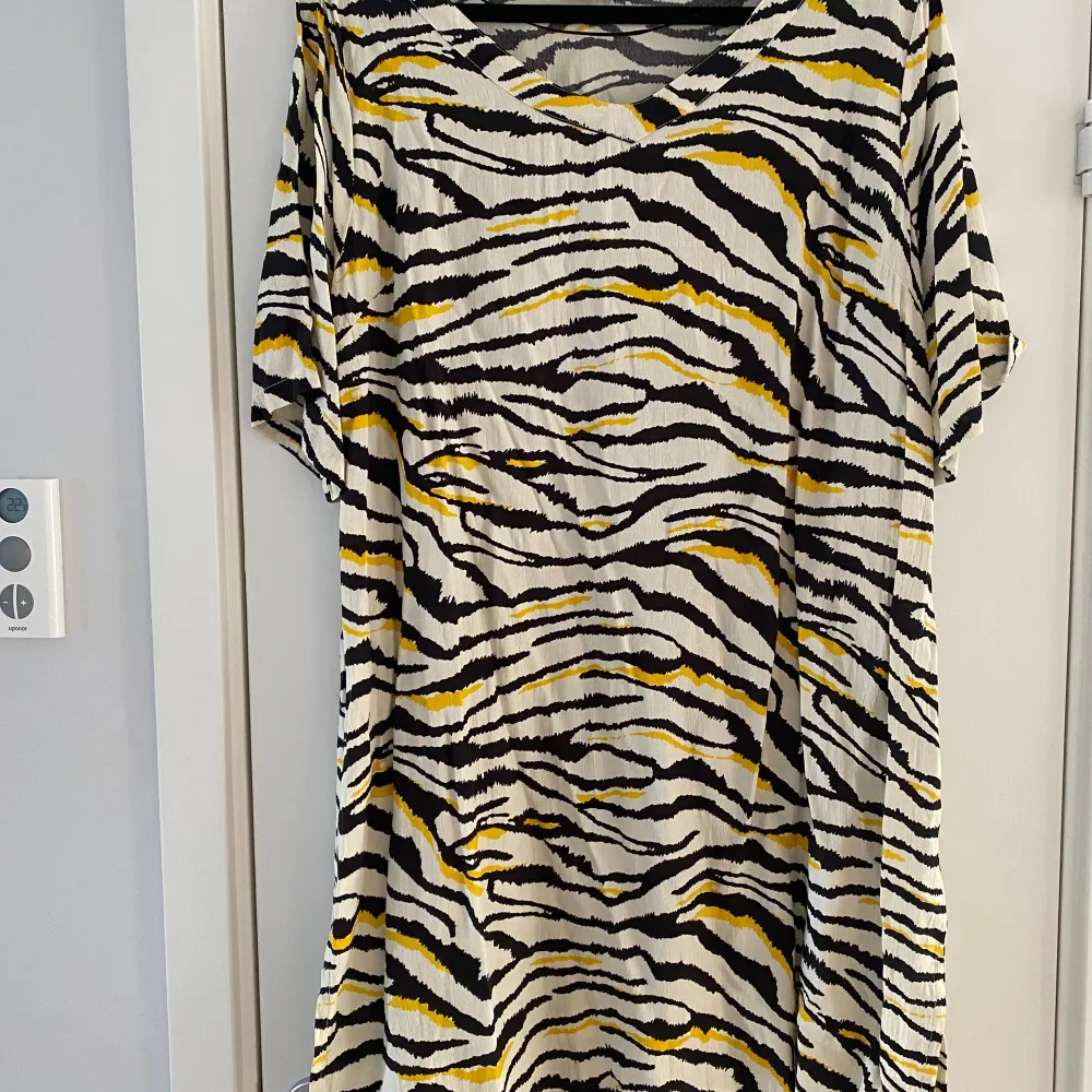 Svart, vit och gul tigermönstrad klänning fr Ahoney i strl L.  Sparsamt använd och i fint begagnat skick.  Viskos   Kommer från ett djur och rökfritt hem.. Klänningar.