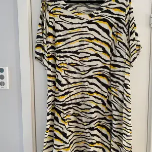 Svart, vit och gul tigermönstrad klänning fr Ahoney i strl L.  Sparsamt använd och i fint begagnat skick.  Viskos   Kommer från ett djur och rökfritt hem.