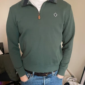 Grön Morris halfzip - Snygg grön zip up med unikt material. Sitter skitbra och inga defekter. Pris kan diskuteras