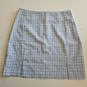 Kjol strl xs - Kort kjol i strl xs. Blåvit-rutig. Två slitsar fram, dragkedja bak. 