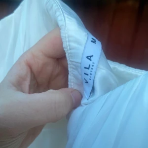 Vit klänning  - Vit klänning. Passar till student el annan festlig tillställning sommartid. Det skira tyger har lossnat från inte tyget på klänningen högersida. Syns inte. Vero Moda st m 