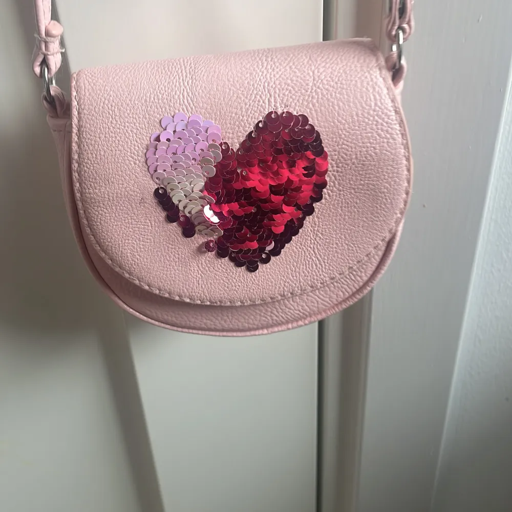 Rosa fin lite handväska med ett hjärta på som kan vara två färger. Asusteet.