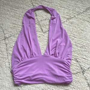 Lila halterneck topp från H&M - Säljer en snygg lila halterneck topp från H&M. Toppen är ärmlös och har en djup urringning. Perfekt för sommarens fester eller en utekväll. Materialet är mjukt och stretchigt, vilket gör den bekväm att bära. Köp direkt eller ge prisförslag 💜