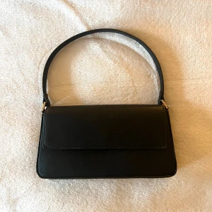 Svart handväska - En lite mindre svart handväska. Perfekt för att mobil, kort mm. Aldrig använt denna.