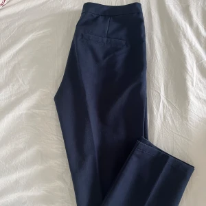 Mörkblå kostymbyxor från Minimum - Mörkblå kostymbyxor från Minimum. Rak passform. Normal-mid waist. Två fickor fram. Säljes då de är för stora för mig. Skulle säga att de passar 34-36. Midja rakt över: 36cm. Innerbenslängd: 67cm. Nyskick. Nypris 700kr. OBS modellen har ett par svarta