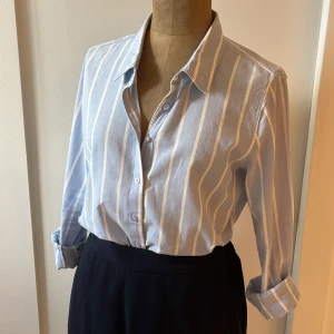 Blå och vit randig skjorta från Bik Bok - Säljer en superfin ljusblå skjorta med vita ränder från Bik Bok i storlek S. Skulle dock säga att den snarare är en M i passformen. Gjord av 100% bomull och är väldigt bekväm att ha på sig. Den har långa ärmar och knappar framtill. Funkar både på kontoret och på landet! 💙