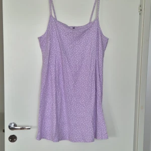Lila klänning med vita blommor  - Helt oanvänd söt sommarklänning! I bra skick! Den är i lavendel med små vita blommor på.