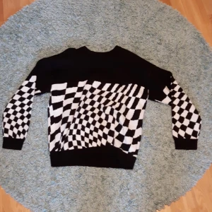 Svart och vit stickad tröja från H&M - Säljer en cool svart och vit stickad tröja från H&M. Tröjan har ett rutigt mönster. Den är långärmad och perfekt för höst och vinter. Tröjan är i nyskick. Jag säljer den för att jag aldrig använder den.  