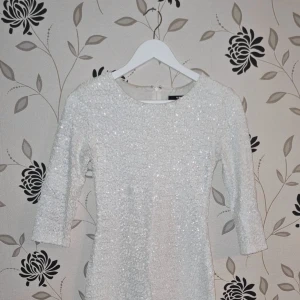TFNC London, vit paljettklänning, Strl: S, Nyår, Fest, Party, Paljetter Sequin - TFNC London, vit paljettklänning, Strl: S, Nyår, Fest, Party, Paljetter Sequin. Missfärgad i nacken - se bilder. Jag har inte försökt att tvätta bort det men det går säkert. Fint skick i övrigt!
