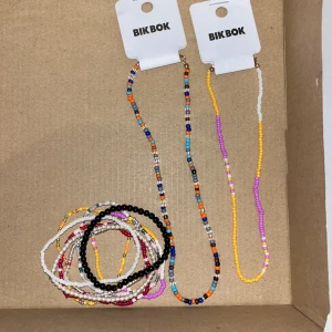 Färgglada pärlhalsband och armband från BikBok - Säljer ett set med färgglada pärlhalsband och armband från BikBok. Halsbanden och armbanden är gjorda av små pärlor i olika färger som orange, blå, lila, vit, svart, röd och gul. Perfekta accessoarer för att liva upp vilken outfit som helst! 💛 Alla armband är inte från Bik Bok !