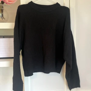 Svart Stickad Tröja - Stickad varm och gosig tröja. Färgen svart. Går ner till midjan och har en liten oversized mysig modell i ärmarna. Fint skick. Från Nelly. Storlek XS. 💗