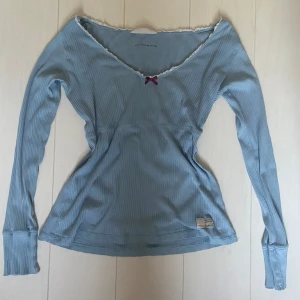 Vintage Odd Molly tröja ljusblå, med rosett och spets - En gammal odd molly tröja med många fina detaljer och en båtkrage med spetsrunt. Kom privat för fler bilder. Fint skick förutom en lagning som knappt syns (noggrannare bild på lagningen på sista bilden). Säljer då den är för stor.