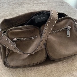 Noella väska stor grå - Så fin Noella väska i färgen grå. I andvänt skick men fortfarande fin, ger lite vintage vibes. Nypris 1200 kr. Buda gärna 