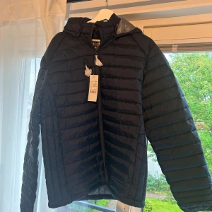 Dunjacka med Leksandslogga - Rensar ur garderoben inför kommande flytt, därav en massa grejer som ska säljas. Helt ny dunjacka med ett litet leksandsmärke på armen. Lite tunnare variant men ack så varm och skön.