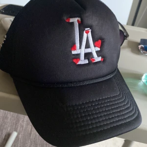 Laidback La keps❤️❤️ -  Dina LA keps är cool och avslappnad med en rak skärm och justerbar passform för perfekt komfort. Logotypen "LA"❤️ är broderad framtill i en kontrasterande färg som ger en sportig touch.Kepsen är tillverkad i slitstarkt material och passar perfekt