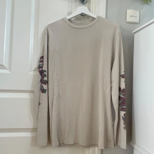 Tröja Daily Paper - En otroligt fin tunn långärmad tröja ifrån Daily Paper med fina detaljer på ärmarna. Tröjan är i ljusbeige färg. Nypris ca 800kr Storlek: L