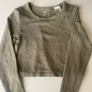 Cropad Träningstopp - Oanvänd Träningstopp i en jättefin grön färg. Modellen är en croptop