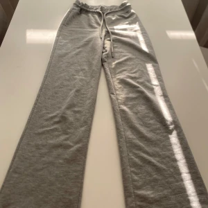 Grå mjukisbyxor - Ett par bekväma grå mjukisbyxor med resår och snörning i midjan. Byxorna har en lös passform och är tillverkade i ett mjukt material.