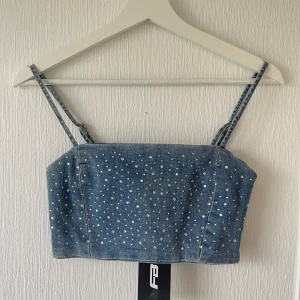 Jeans topp - Väldigt snygg jeans topp med stenar både fram och bak. Dragkedja på vänster sida. Ingen stretch. Justerbara axelband. 