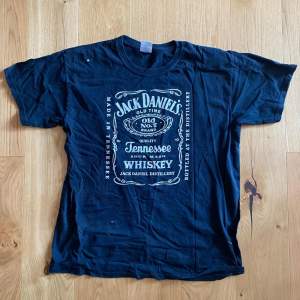 En svart t-shirt från Gildan med Jack Daniel's tryck på framsidan. T-shirten är tillverkad av tung bomull och har korta ärmar.