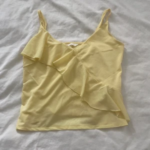 Ljusgul topp med volang  - Säljer denna då den inte kommer till användning. Kontakta mig vid eventuella frågor. Köp nu är på!❤️