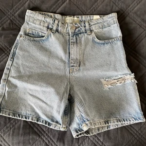 Ljusblå jeansshorts med hål - Ljusblå shorts som är oanvända, enbart testade. Säljer då de är för stora för mig och väntat på att växa i dom. Köpte ifrån Chiquelle för 399 kr. Fin detalj på vänster ben.