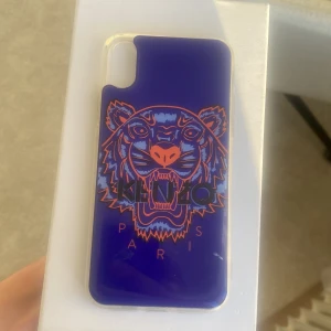 Kenzo IPhone X Mobilskal  - Kenzo mobilskal för IPhone X. Mörkblått, ljusblått, oranget. Införskaffat för ≈3 år sedan. Knappt använt överhuvudtaget. Strålande skick förutom liten blå ”skråma” (se andra bild). Nypris: 500 kr  (Låda ingår)