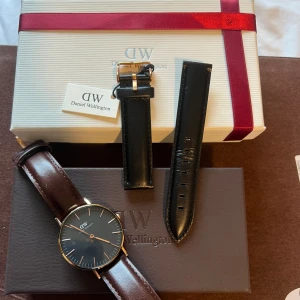 Daniel Wellington klocka  - Daniel Wellington klocka, brunt läderarmband och svart urtavla. Kommer med helt nytt oanvänt svart läderarmband.  Box och manual finns. 