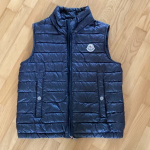 Moncler väst  - Säljer nu min Moncler väst då den inte passar. Det är en lite äldre model men märks inte då den är väldigt snygg. Den är 7/10 i skick därav priset. Storleken är ungefär 152cm. Priset kan diskuteras vid snabb affär. Fråga vad ni vill!