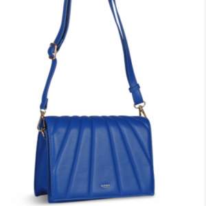 En Royal blue handväska med reglerbar och avtagbar rem från Ulrika Design. Mått: bredd 23cm, höjd 17cm, djup 8cm i botten. Aldrig använd så väldigt fint skick. Nypris 699kr