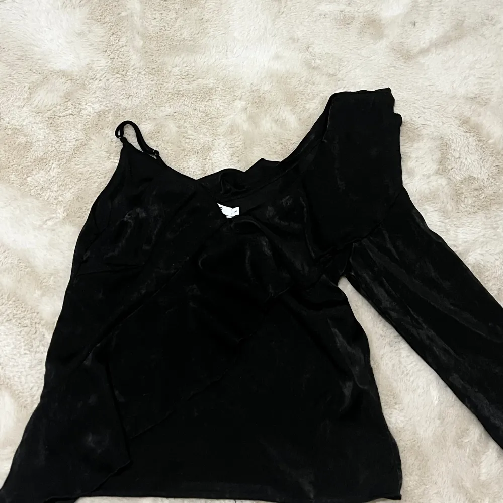 Säljer denna fina svarta one shoulder tröja från NA-KD. Den är i storlek 36. Tröjan är lite nopprig🥰. Blusar.