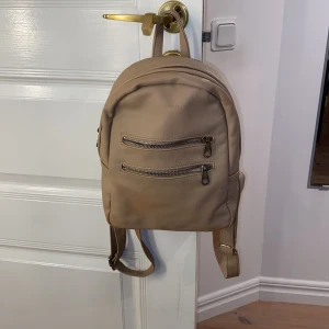 Ryggsäck liten - Liten beige gullig ryggsäck som inte kommer till användning