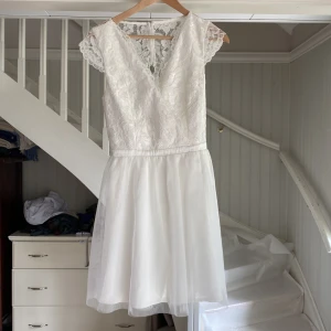 Vit klänning - Vit klänning som passar perfekt till skolavslutningen. Använd en gång. 38 cm mätt rakt över axlarna. 35 cm mätt rakt över midjan. Köptes för 1000kr 2023, säljs inte längre.