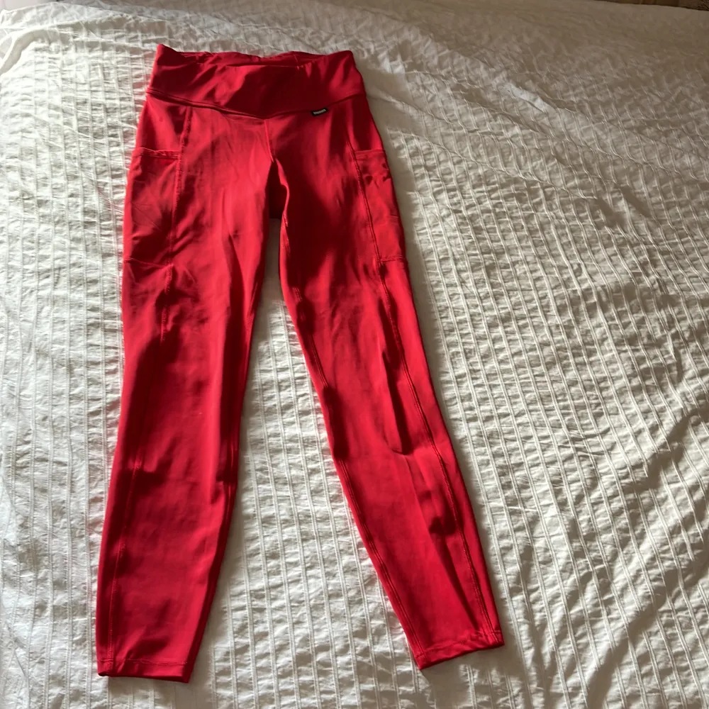 Snygga röda tights med tre fickor. Två större på sidan av låren och en mindre bak i midjan. Finns tillhörande tröja att köpa till. . Sport & träning.