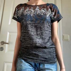 T-shirt - Jätte cool metrofive t-shirt med fina detaljer. Röd, blå och vit färg mönstertryck på framsidan samt silvriga metall rhinestones/stenar. Liten öppning i ryggen. Längst ner på tröjan är det en insydd minikjol runt som tjatar till tröjan runt höften💝