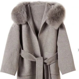 Kappa med päls - Beige/ grå Kappa. Den är väl andvänd och har små slitash som inte syns. Så som att någon knapp på pälsen lossnat men det går enkelt att sy till.  Pälsen på kappan är avtagbar på armarna och luvan. 