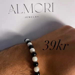 Armband från Almori Jewelry - Ett elegant armband från Almori Jewelry med svarta och vita pärlor. Armbandet har en enkel och stilren design.